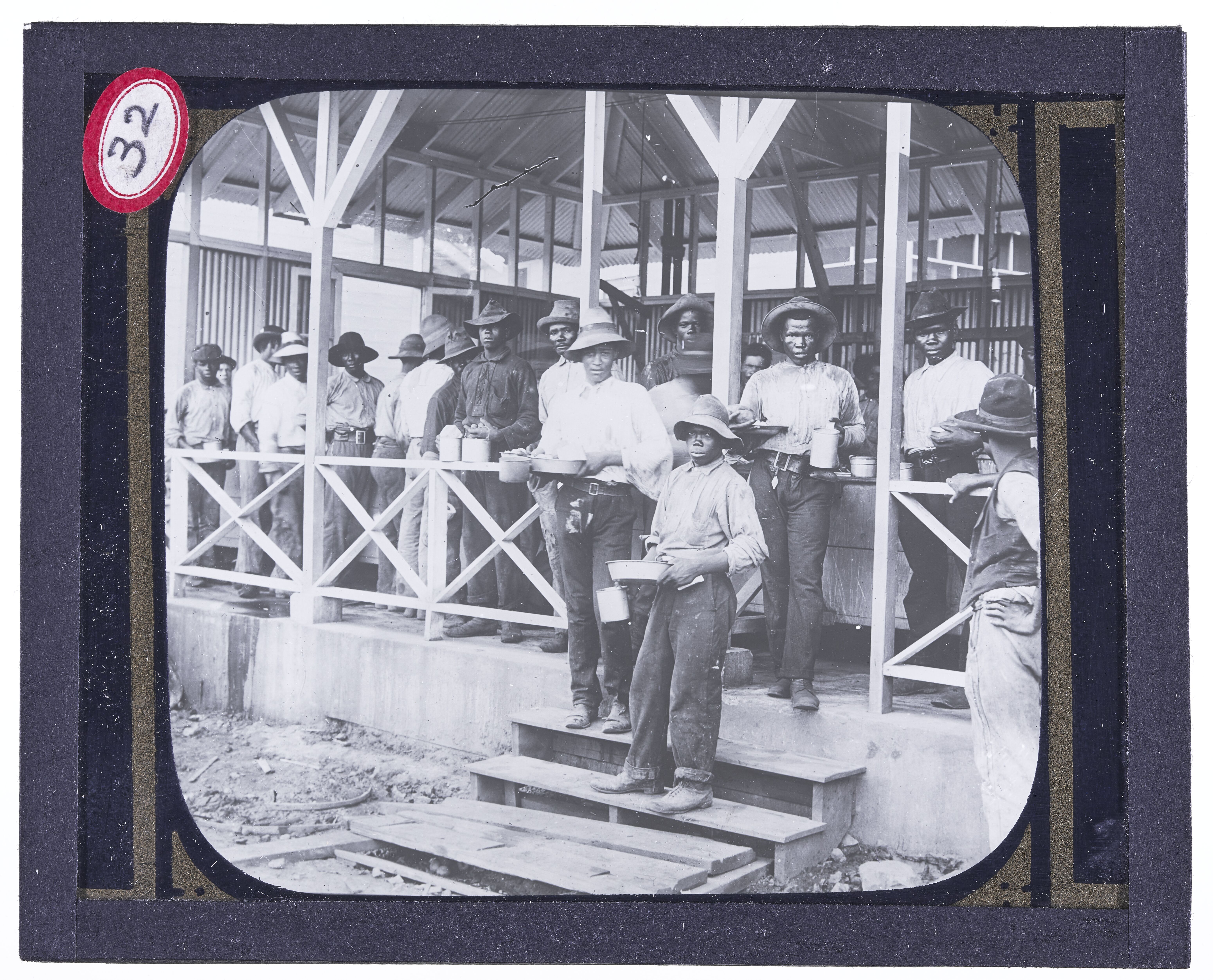 Men of color standing on a porch, eating
