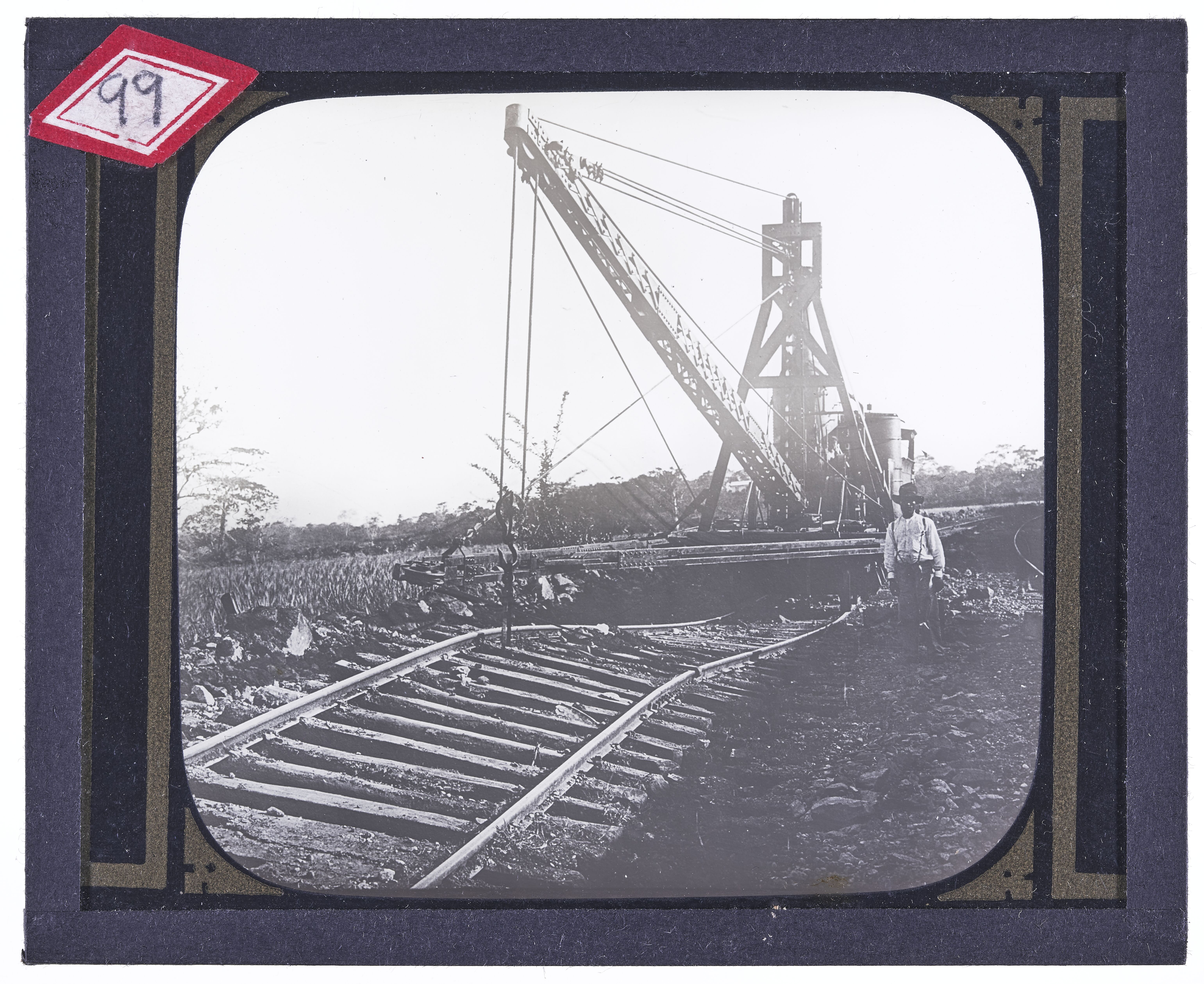 Black man standing beside a railroad derrick on curved tracks
