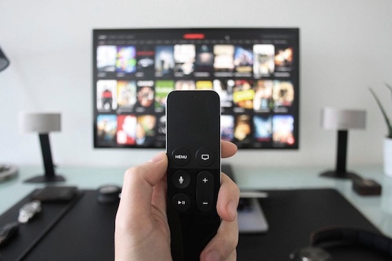 close up of a TV remote with a TV in the background