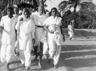 Gandhi walking with Manu Gandhi and Amtul Salaam